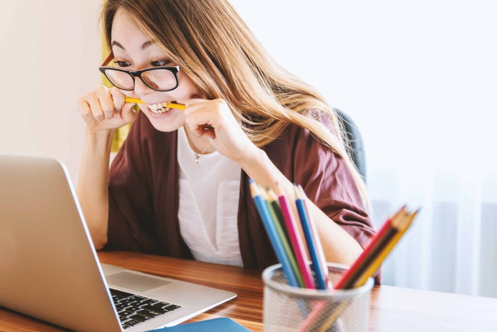 Stressed woman working at the computer bitting on the pencil