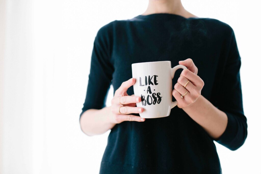 A woman holding a cup that says like a boss symbolizes her success