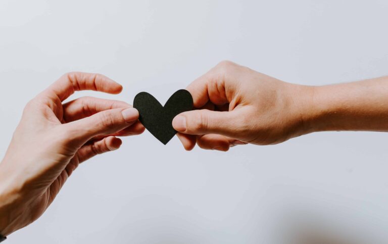 Two hands holding a paper heart symbolize the importance of self-love